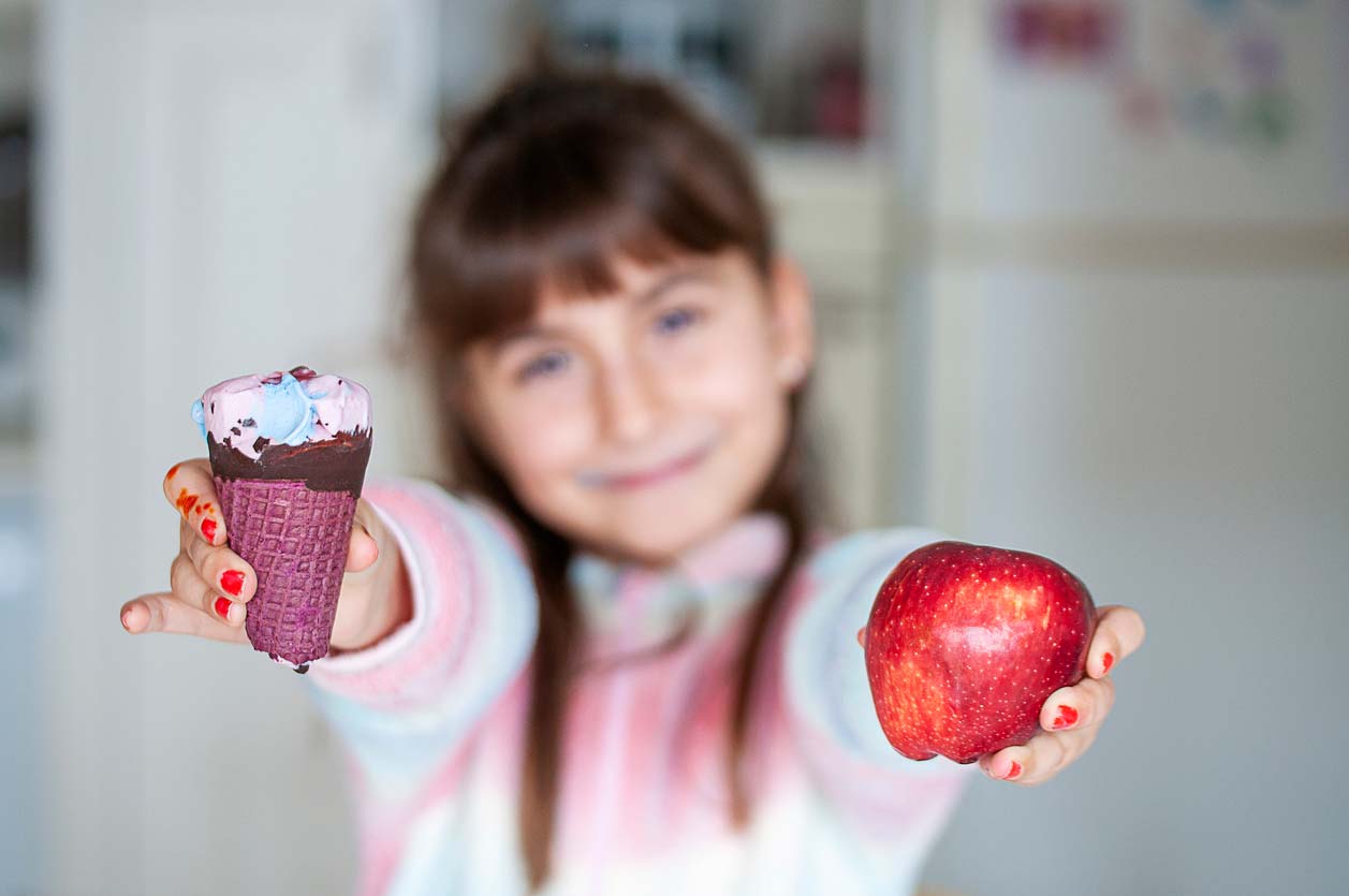 girl holding ice cream cone and an apple