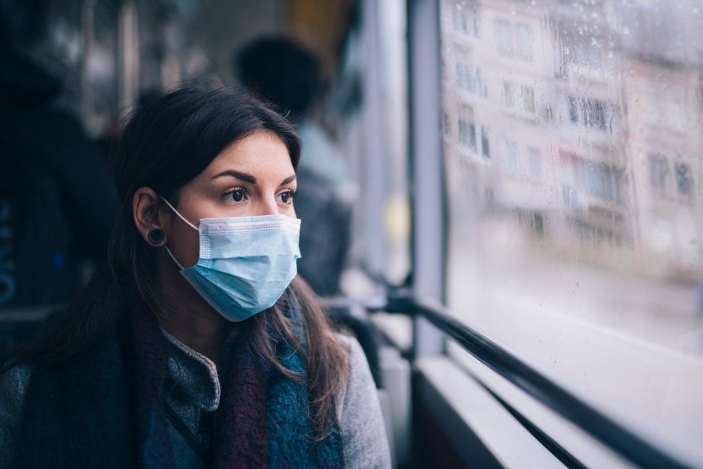 Woman with surgical face mask on riding a bus