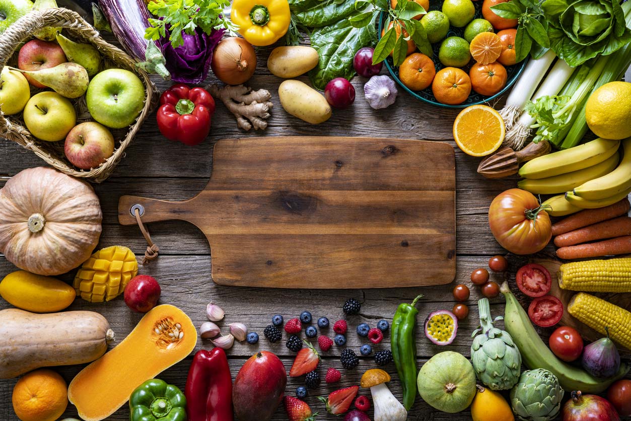 preparing a vegan charcuterie board - wooden board surrounded by fruits and vegetables