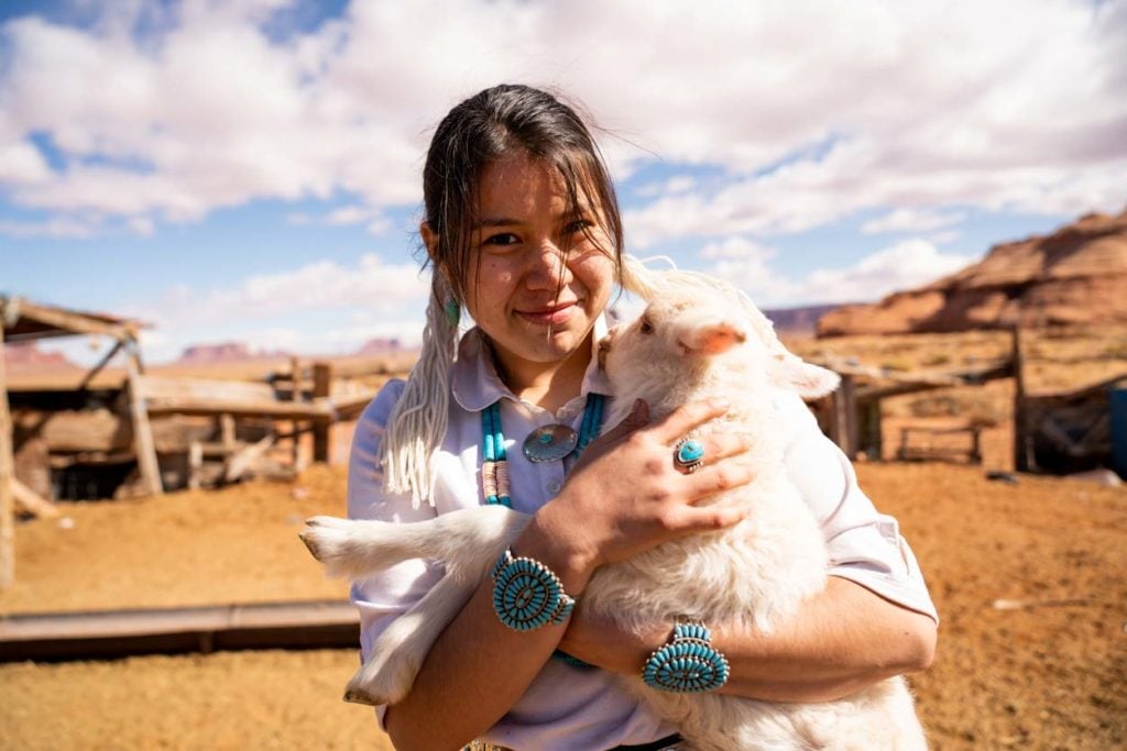 A Navajo girl holding a lamb on a reservation