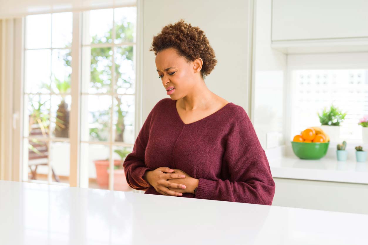 woman grimacing while holding stomach