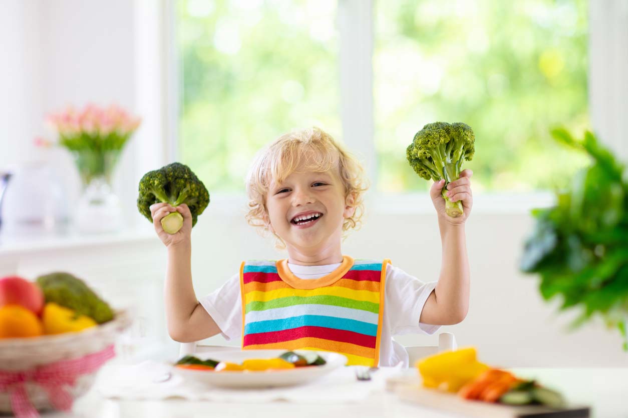 young child excitedly holding broccoli