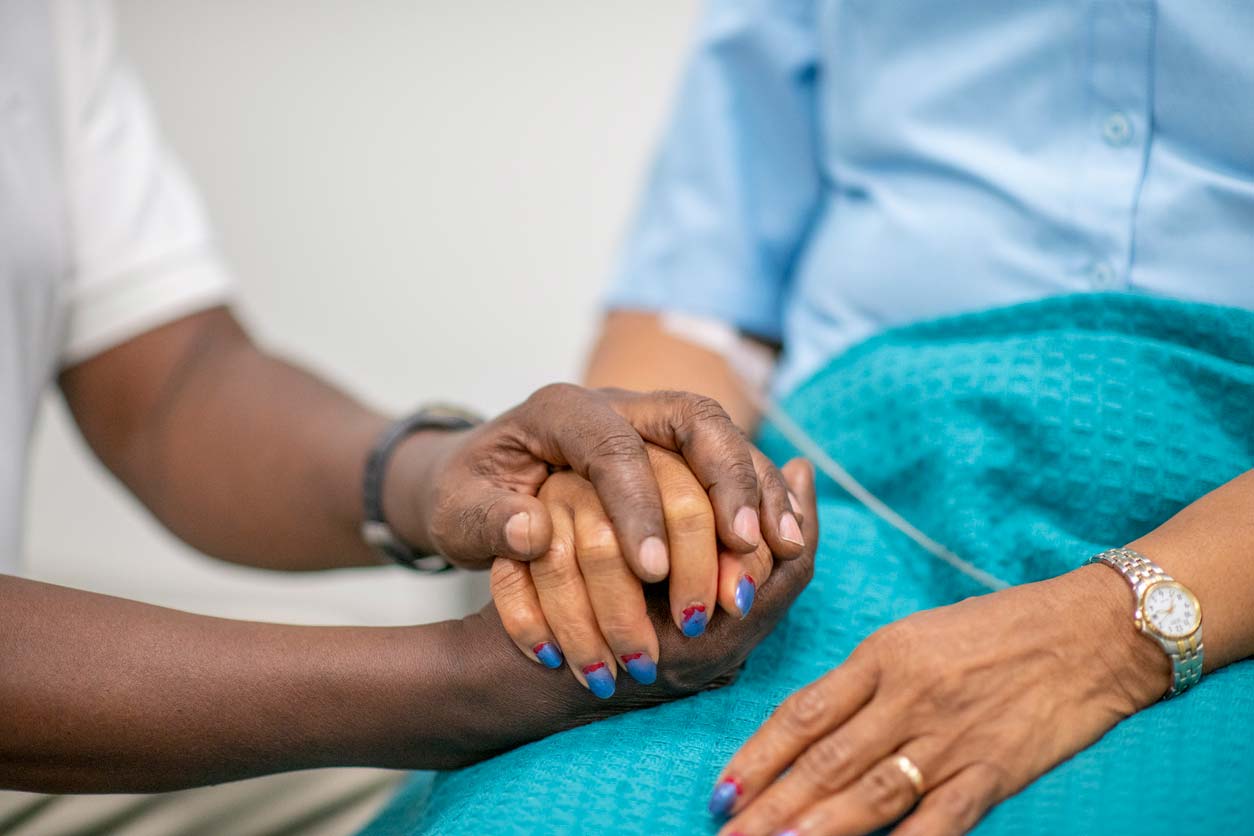 elderly patient being comforted with hands from medical professional