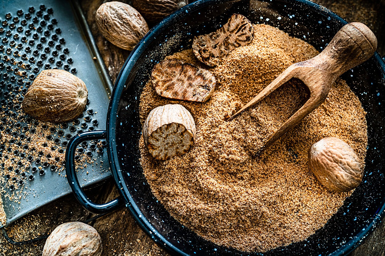 nutmeg seeds and ground nutmeg shot on rustic wood garden table