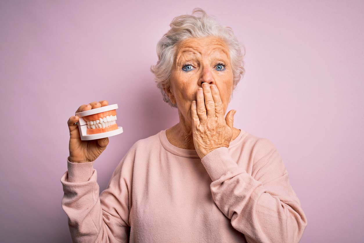 senior woman holding denture teeth