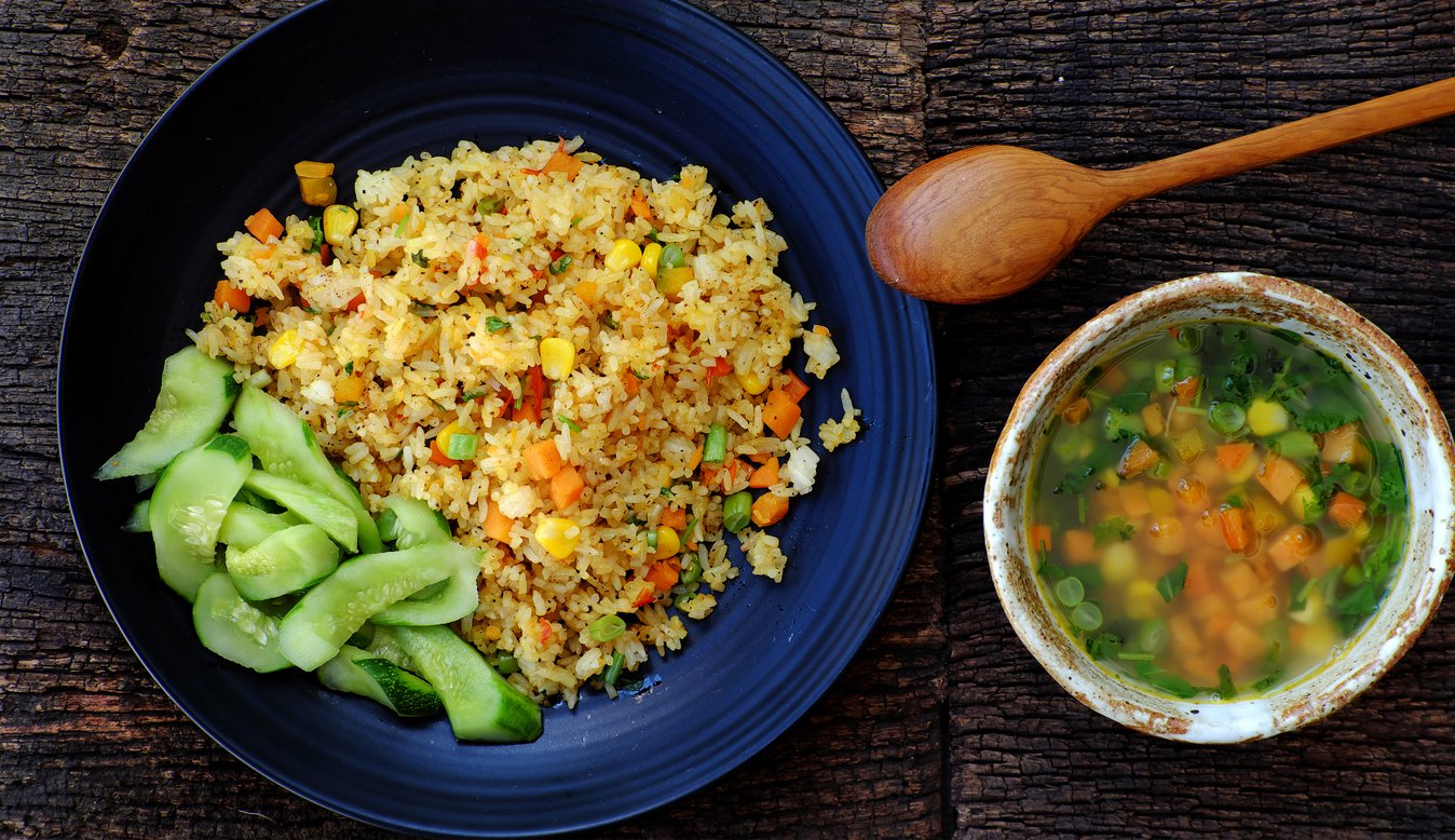 High view woman hand prepare food for quick dinner, Vegan meal with pilaw fried rice with soup from vegetables as carrot, corn, string bean, vegetarian dish in yellow, delicious Vietnamese cuisine