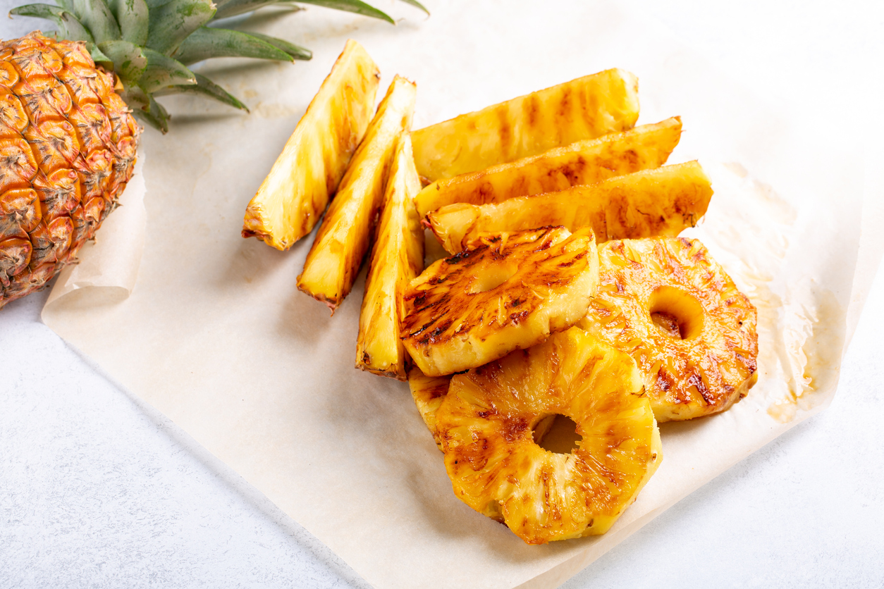 Heap of grilled pineapple slices on white background.