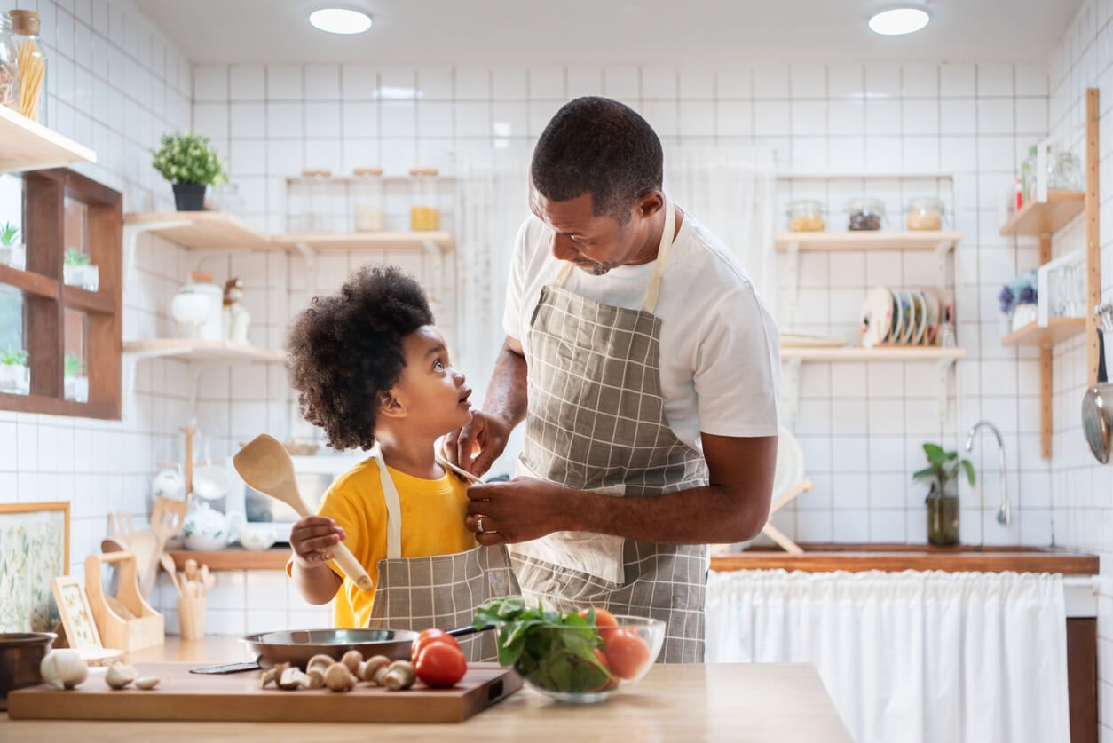 happy African father and son dress up together before cooking in the white kitchen