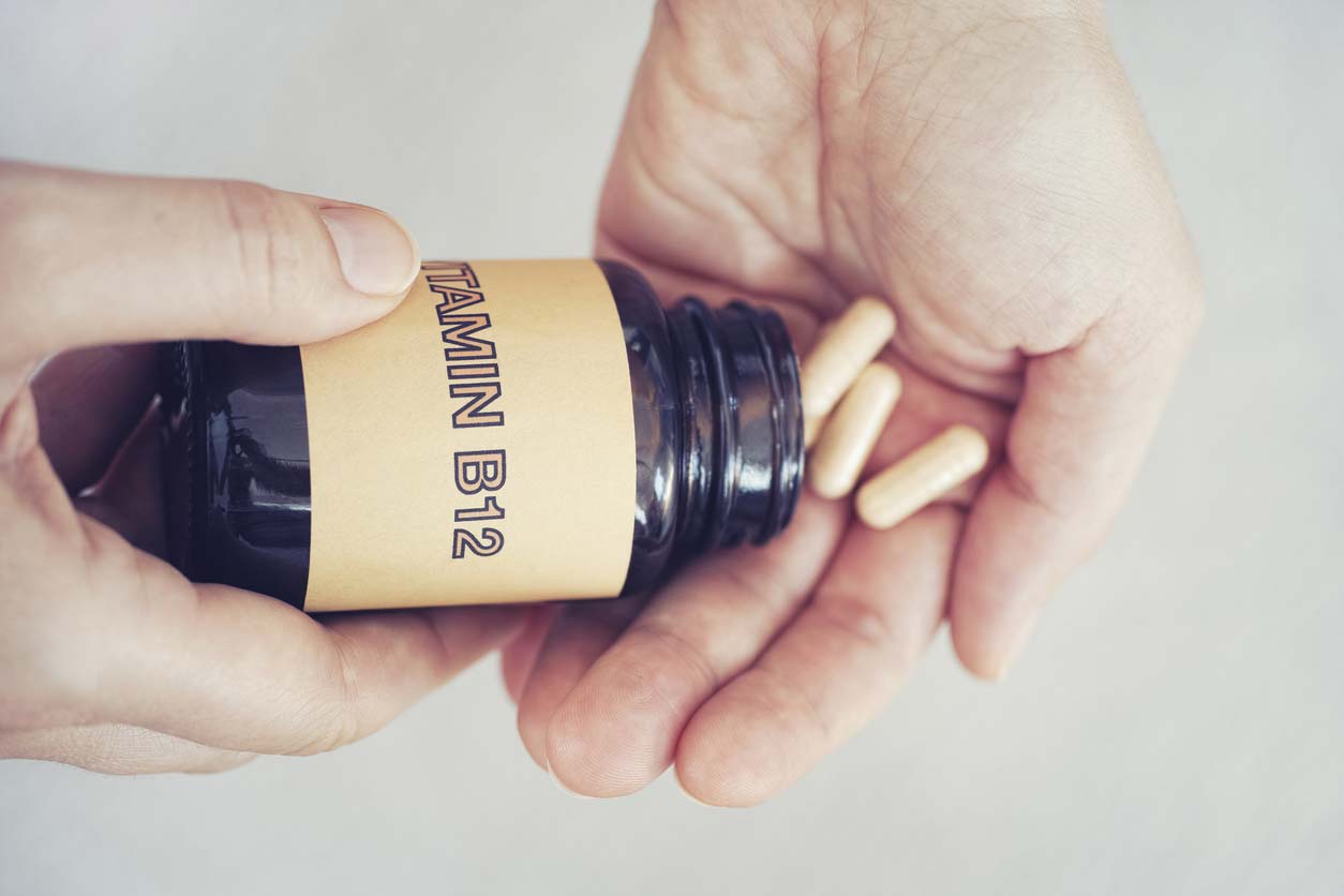 person taking out vitamin b12 capsules from bottle