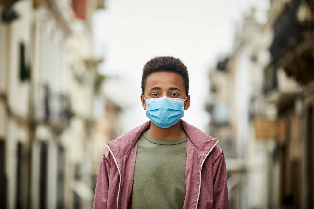 Health inequality among people of color - black boy with face mask on stands alone