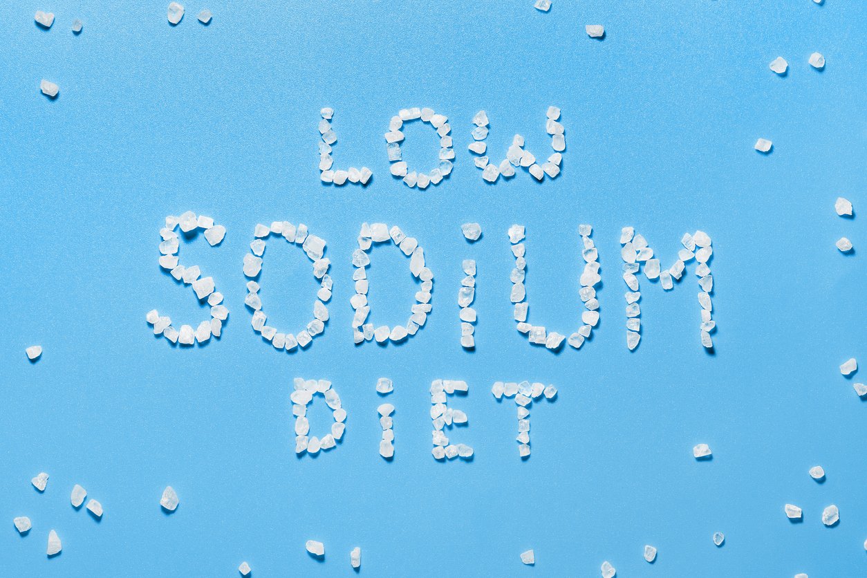 The concept of a low sodium diet. Prevention of hypertension and heart disease. Salt crystals on blue background.