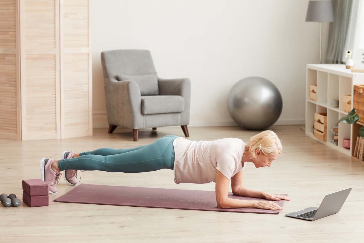 Senior woman doing weight-bearing exercise on yoga mat