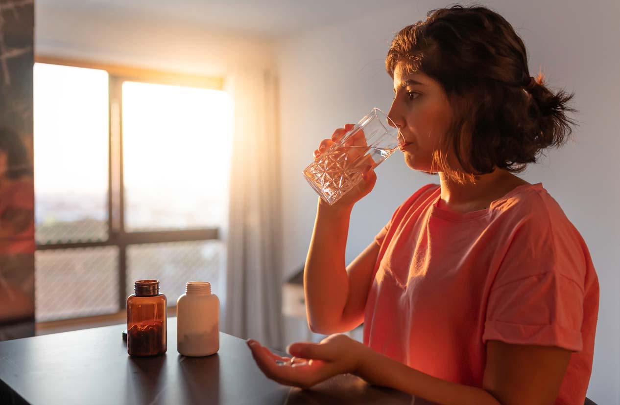 Woman taking supplements with a glass of water