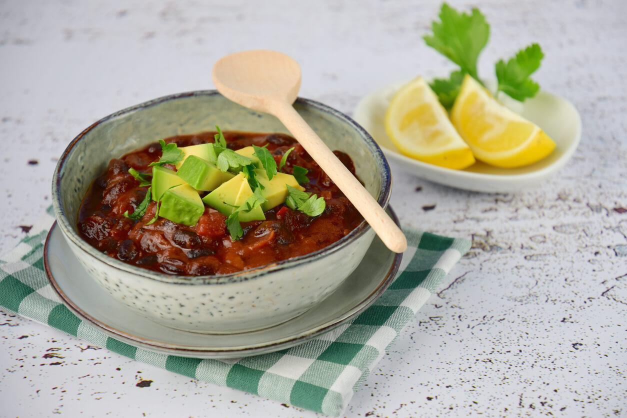 homemade vegan black bean chili tomato soup with diced avocado and chopped parsley