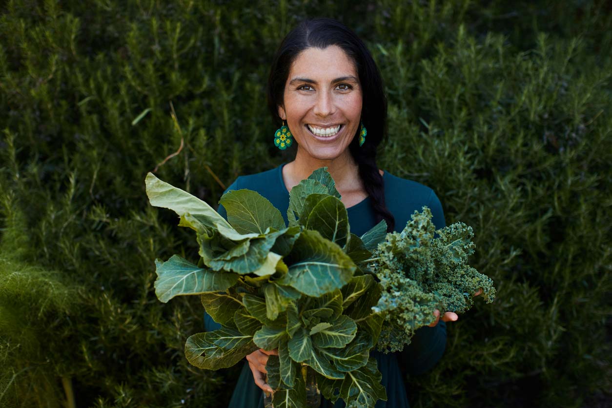 Happy woman holding fresh-picked green leafy vegetables