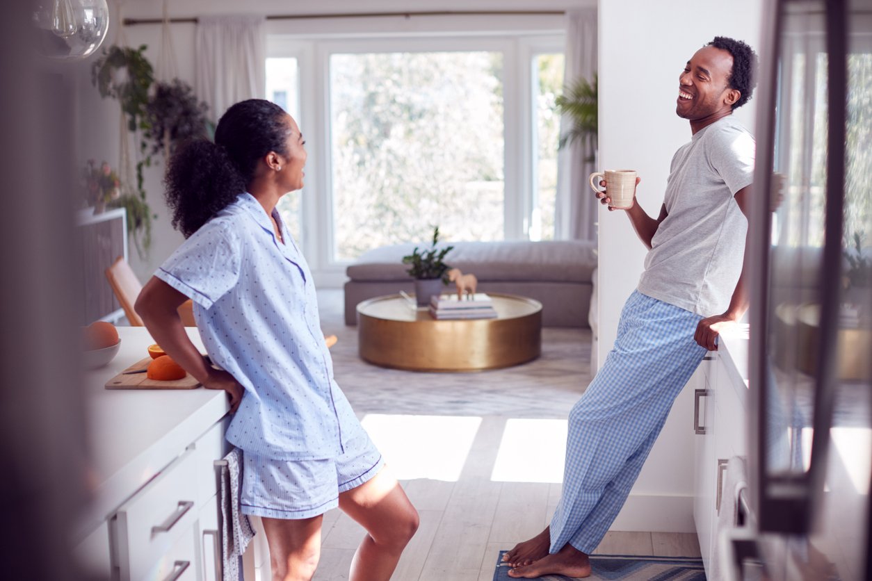 Couple Wearing Pyjamas Talking In Kitchen At Home Together