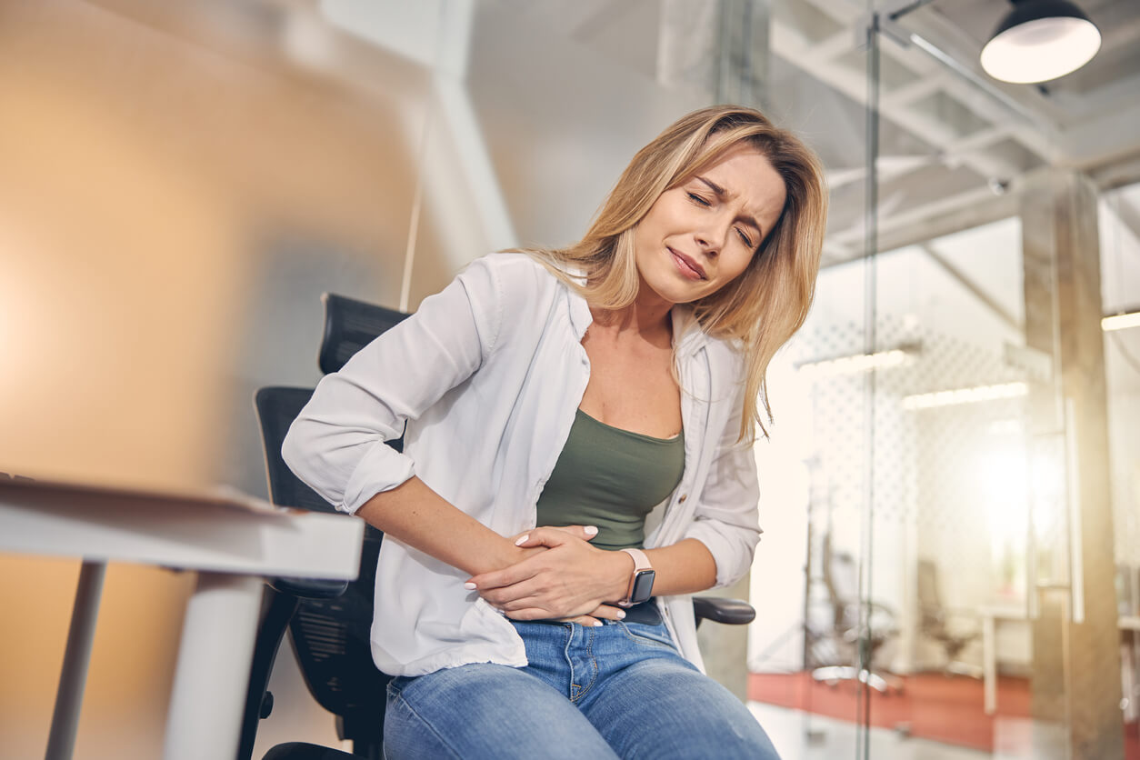 upset woman suffering from stomachache in the office