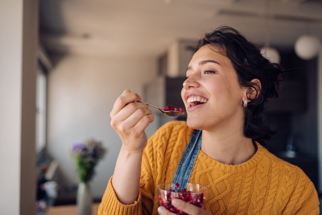 portrait of a happy girl enjoying fresh pomegranate at home