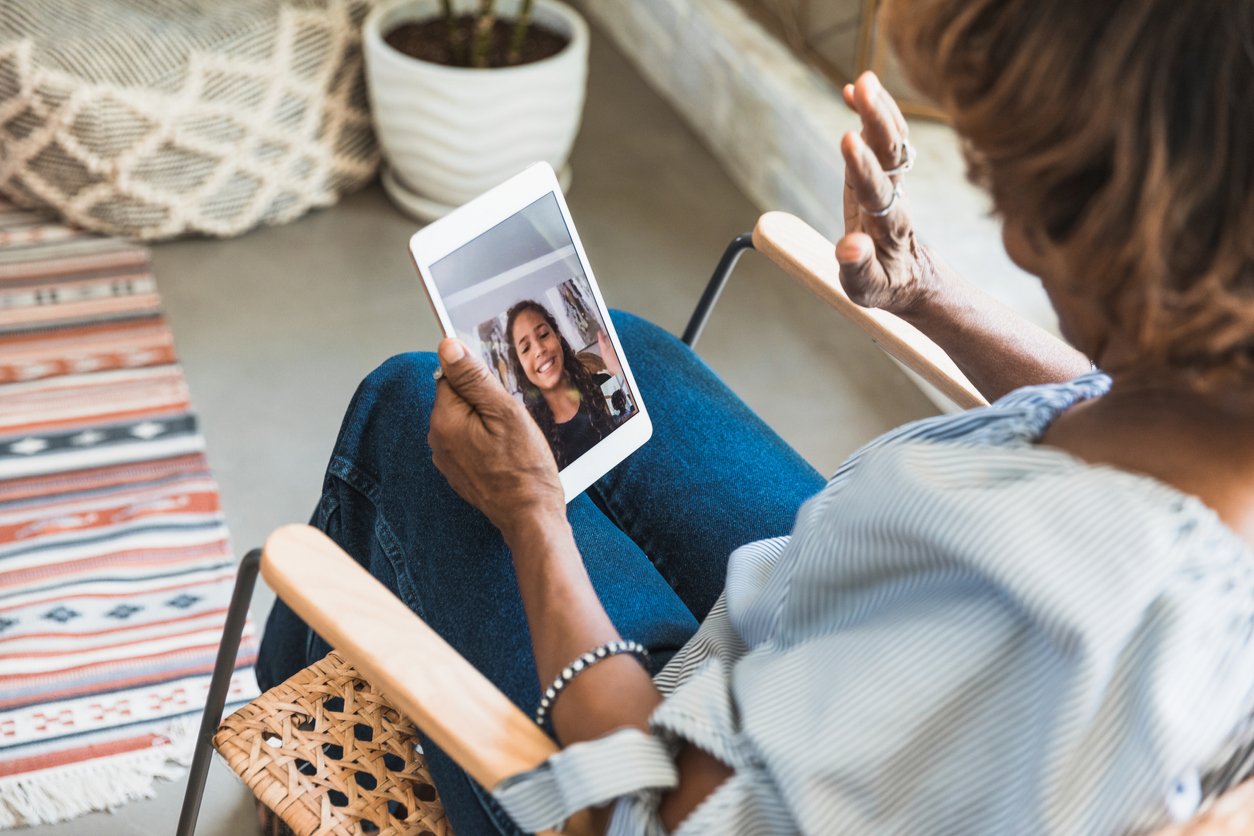 Grandmother video conferences with granddaughter on digital tablet