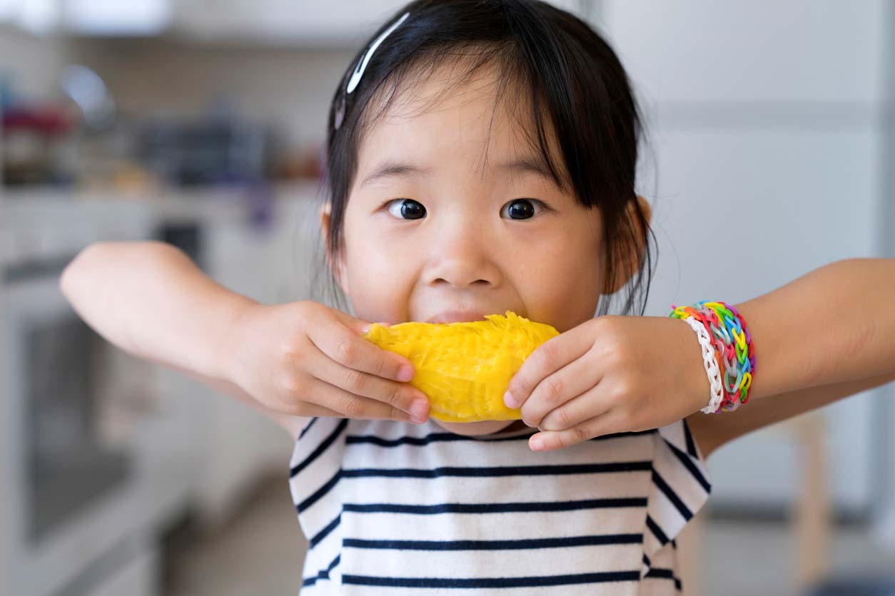 young girl eating a mango