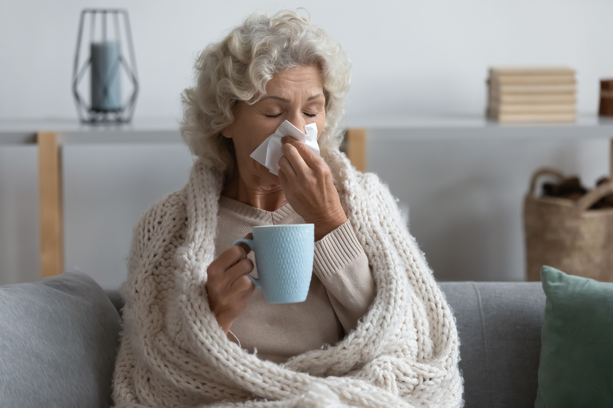 Sick mature woman wrapped blanket blowing running nose, feeling unhealthy
