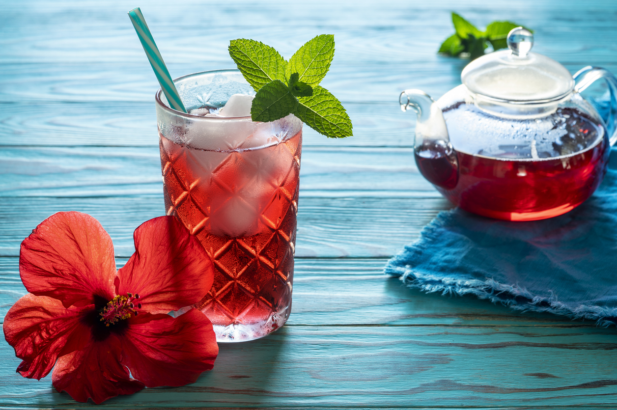 Hibiscus iced tea with flower and teapot on tropical turquoise wood Mexican beverage called Agua de Jamaica
