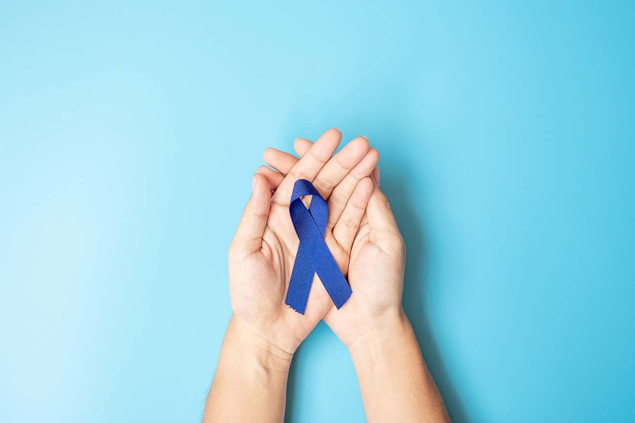 hands holding blue ribbon for cancer awareness