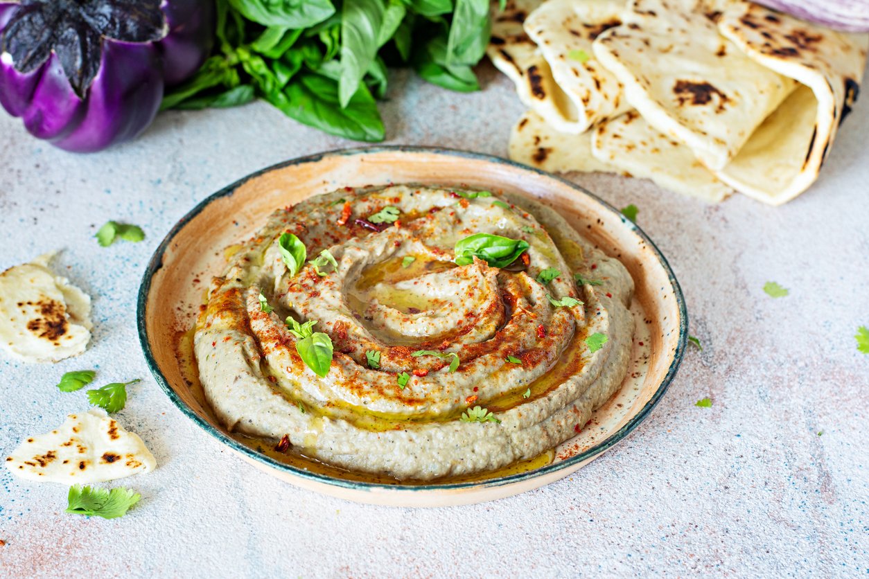 An oriental dish of baked eggplant babaganush (eggplant puree) with spices, herbs, lettuce and oriental flatbreads.