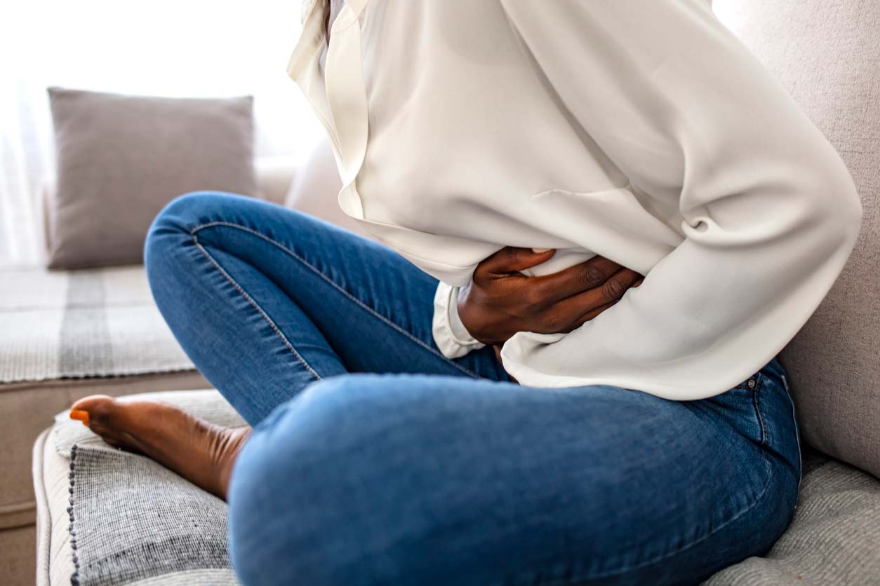 woman holding stomach on couch
