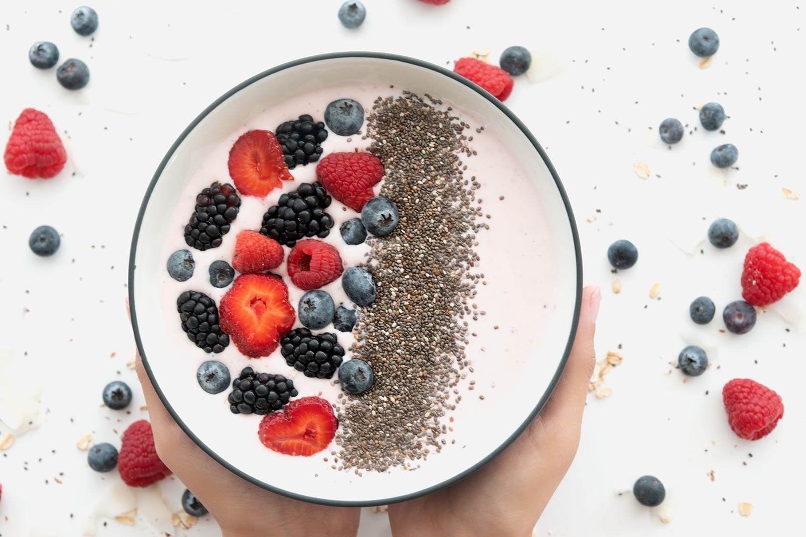 Hands holding a bowl of cashew yogurt with chia seeds and berries — a healthy breakfast