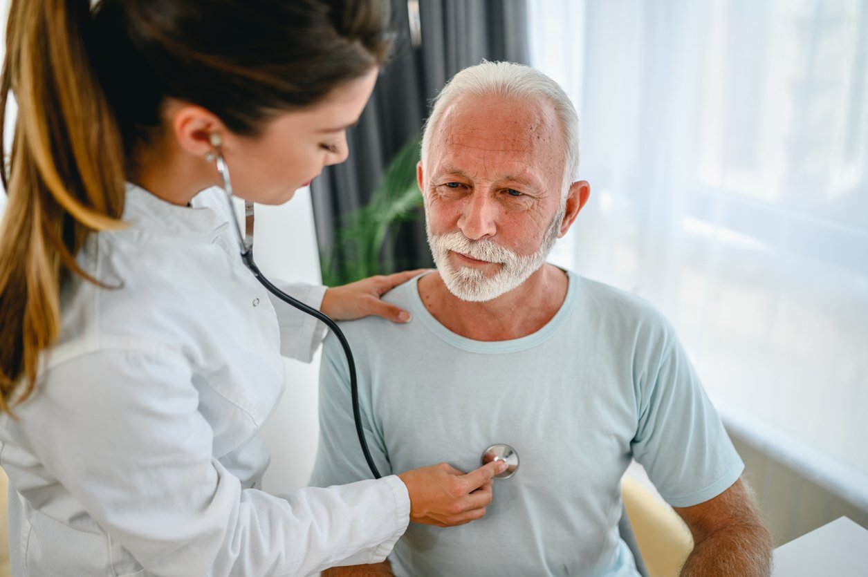 Female doctor using stethoscope listening to senior patients breathing