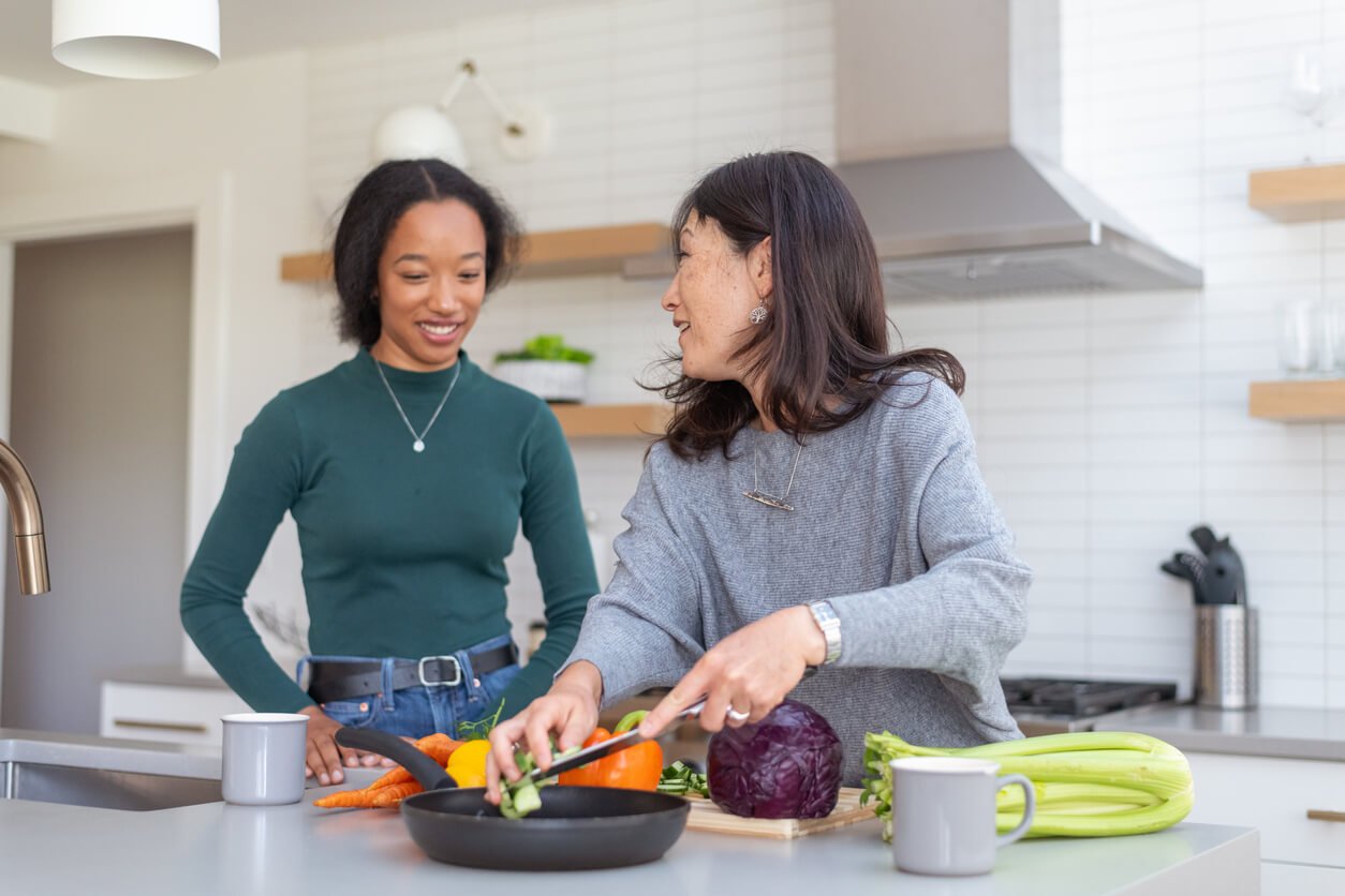 young adult woman helping mother cook healthy dinner