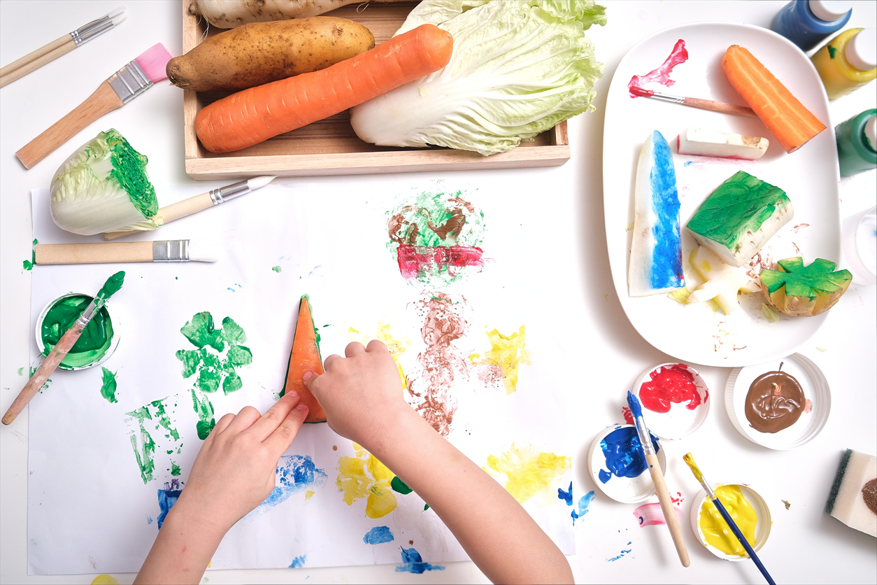 Top view close up of toddler boy child hands, kid making artwork from vegetable stamping at home, Fun art and crafts for toddlers