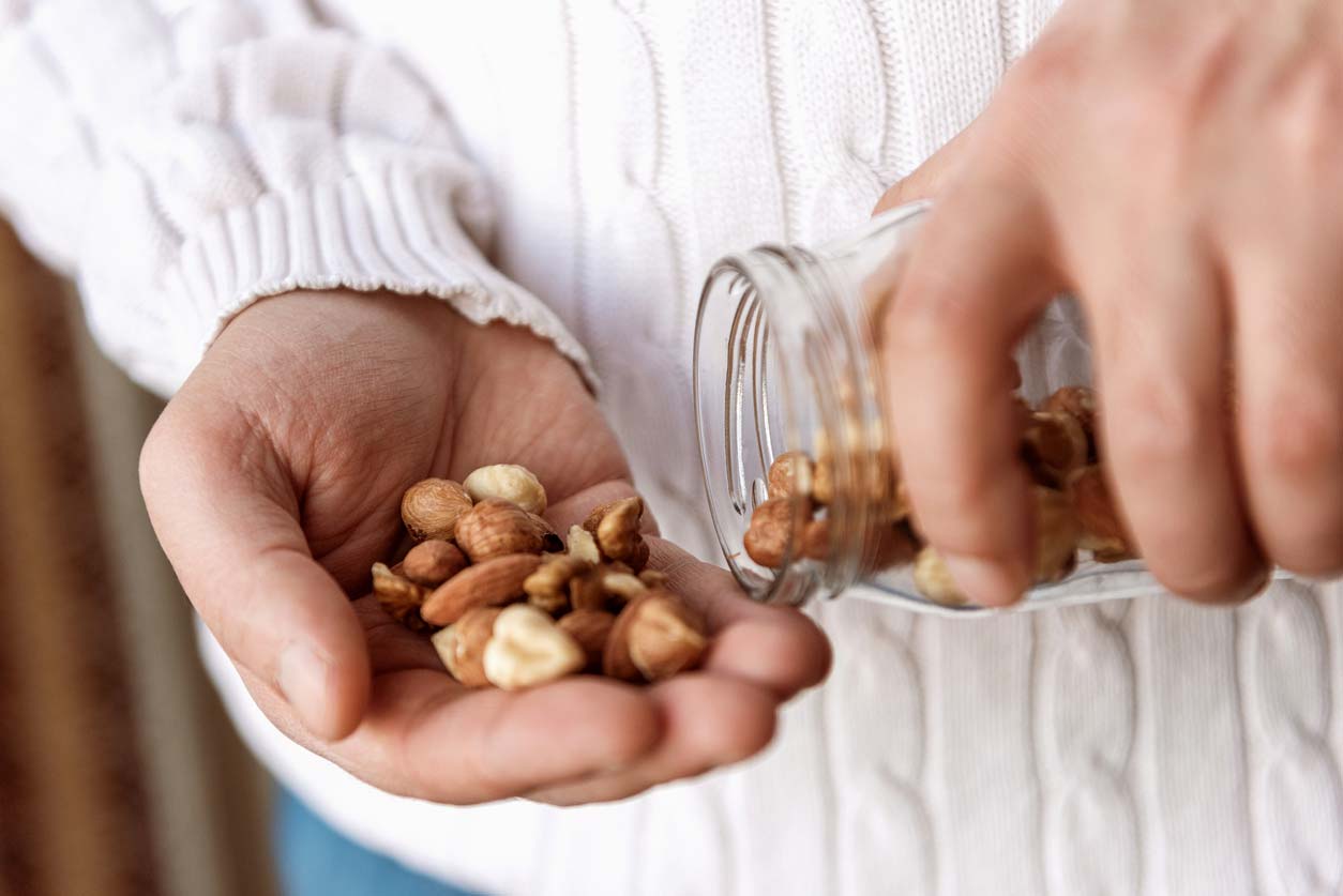 Pouring almonds and hazelnuts out of a glass jar into hands