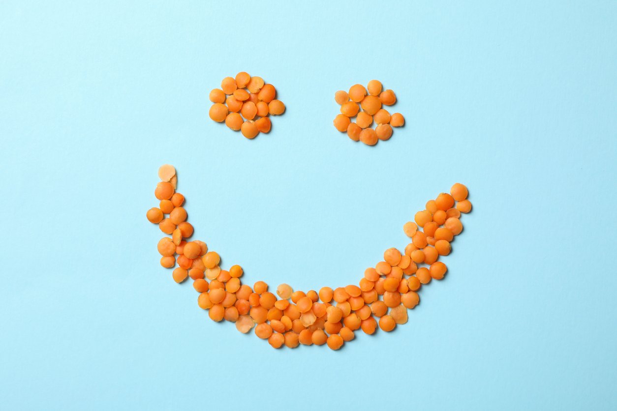 Happy face made of red legumes on blue background