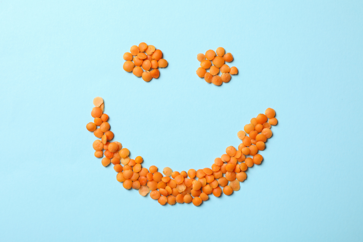 Happy face made of red legumes on blue background