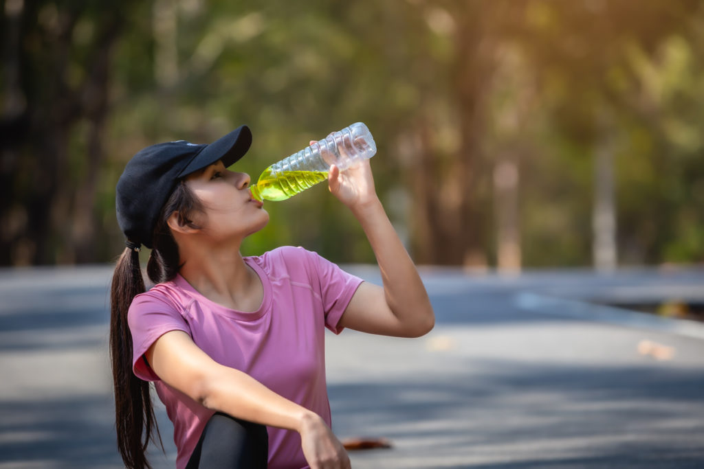 Woman drinking sports drink out of a plastic bottle
