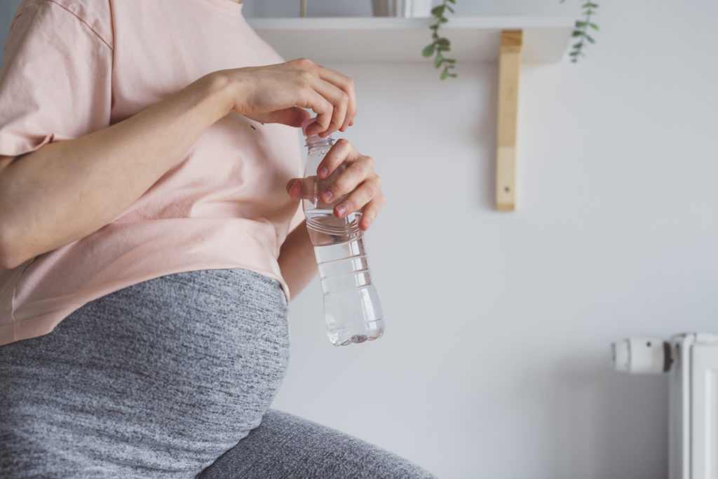 Young pregnant woman holding a plastic water bottle