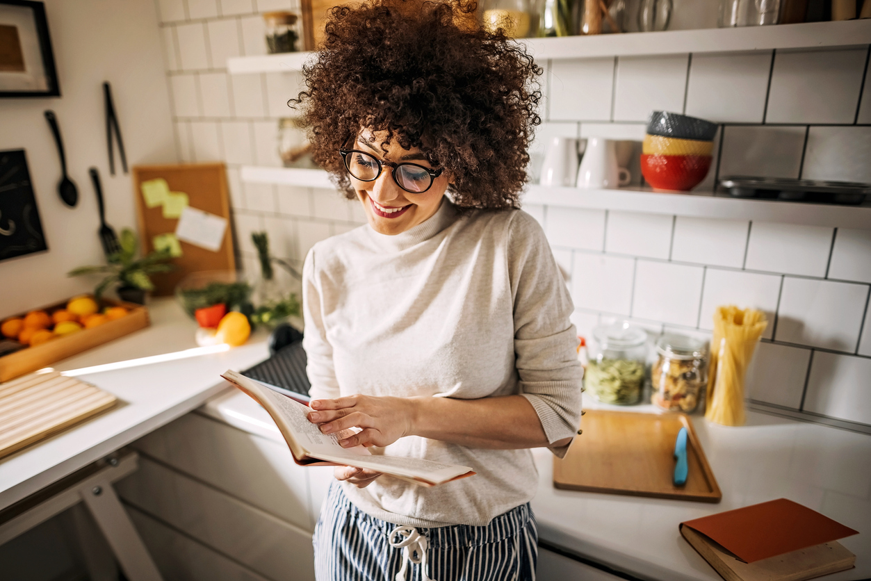 Young women reading recipe for meal, preparing food