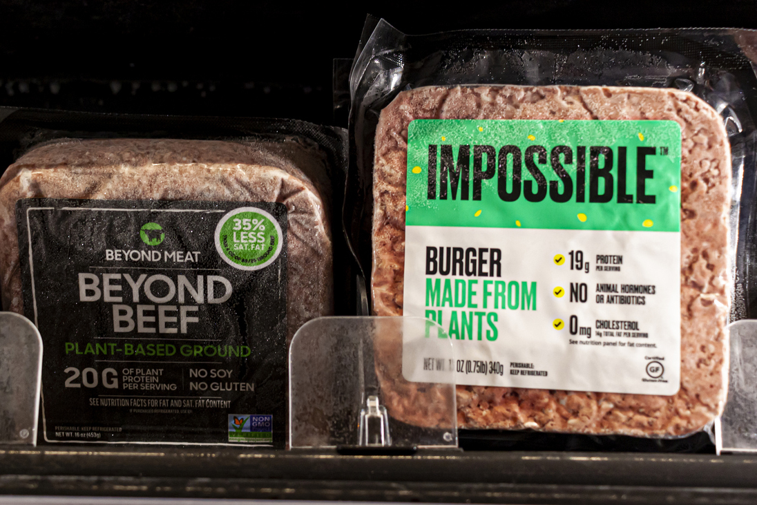 Two popular vegan meat alternative brands Impossible and Beyond beef are sold side by side on a grocery shelf.