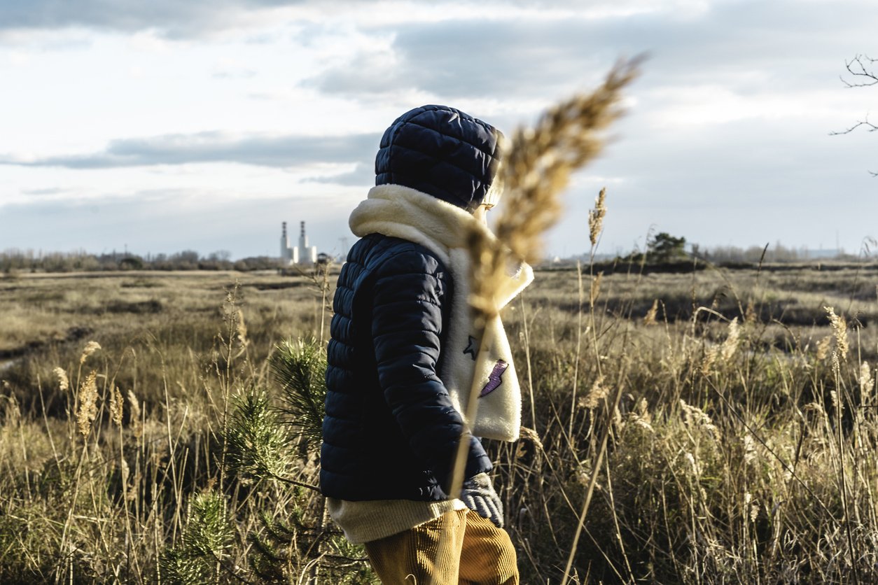 back view of a child wearing winter clothes walking with wild landscape