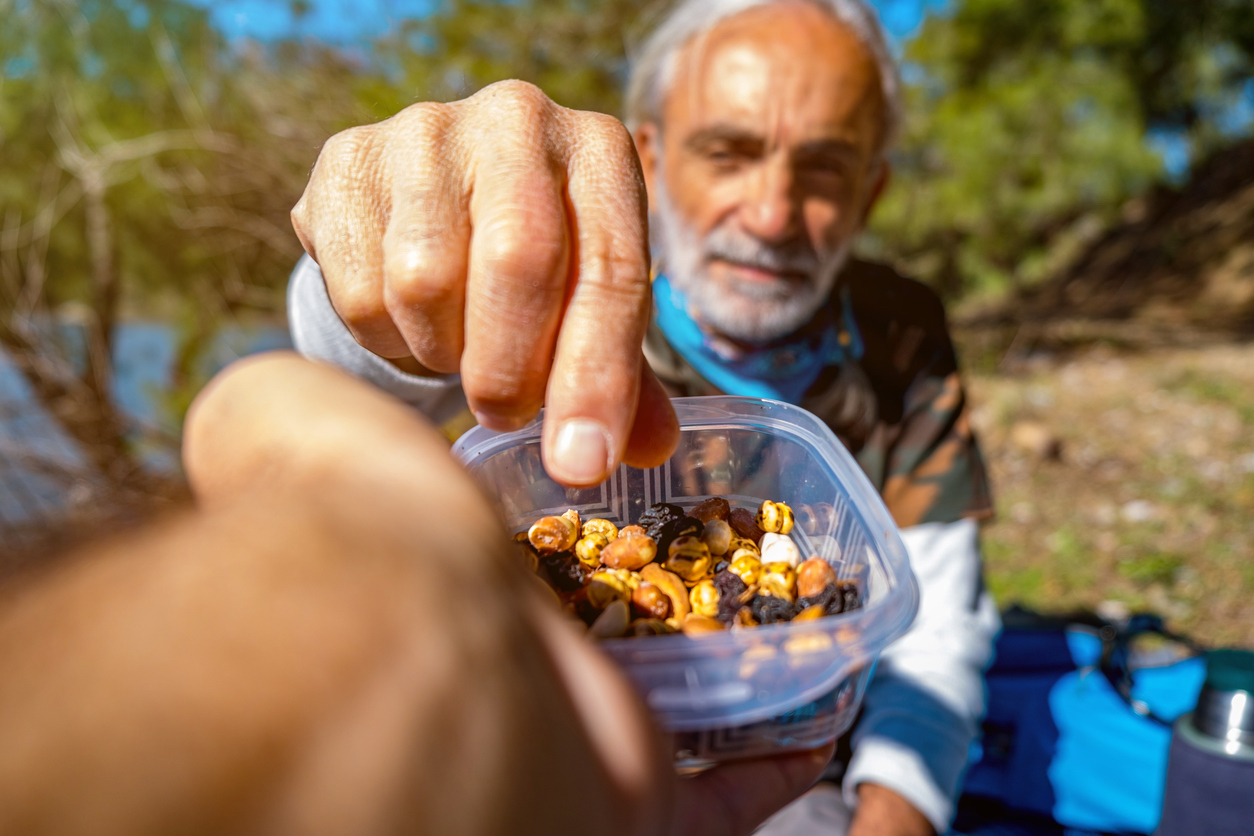 Old man eating healthy nuts in nature