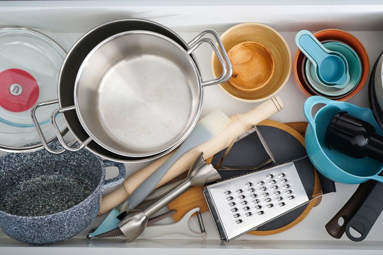 Open drawer with different utensils in kitchen, top view.