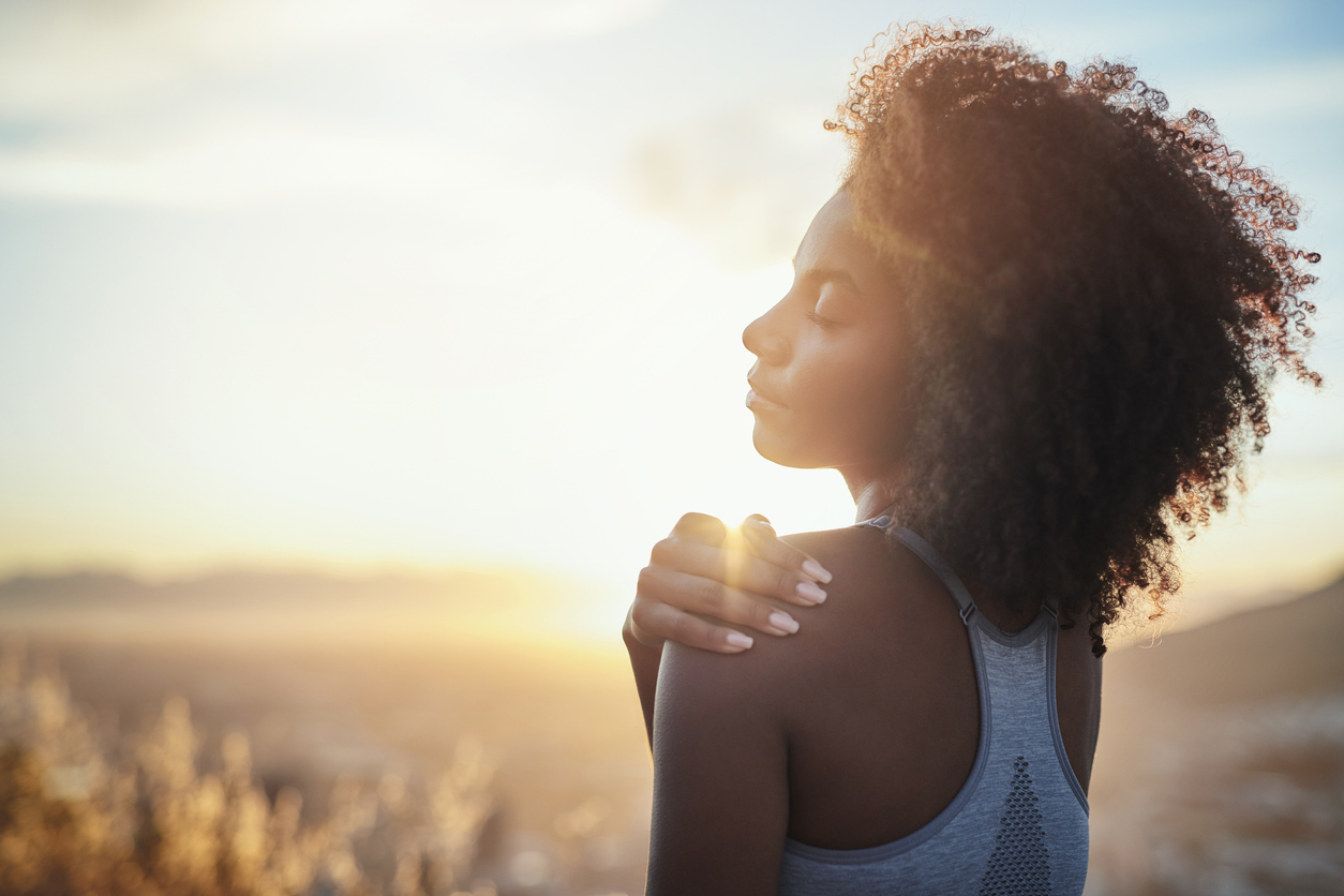 Shot of a young woman touching her shoulder while out for a run