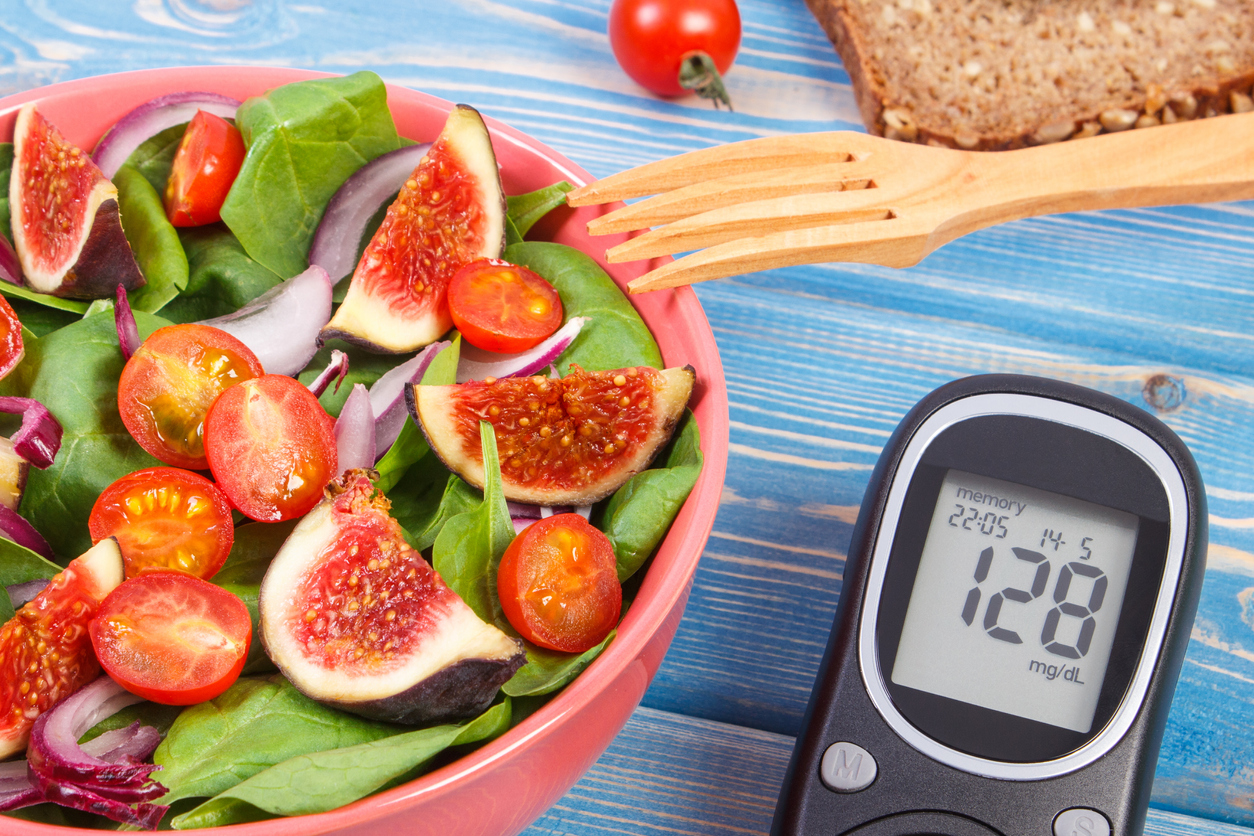 Fruit and vegetable salad and glucose meter with result of measurement sugar level, concept of diabetes, diet, healthy lifestyles and nutrition
