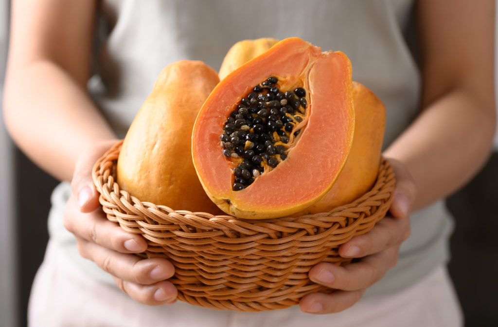 Hands holding a basket with cut papaya