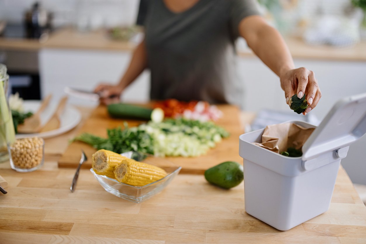 Woman putting organic waste in compost bin