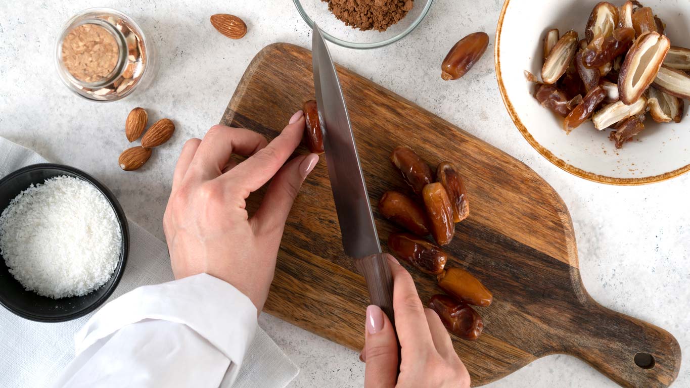 hands cutting dates on cutting board