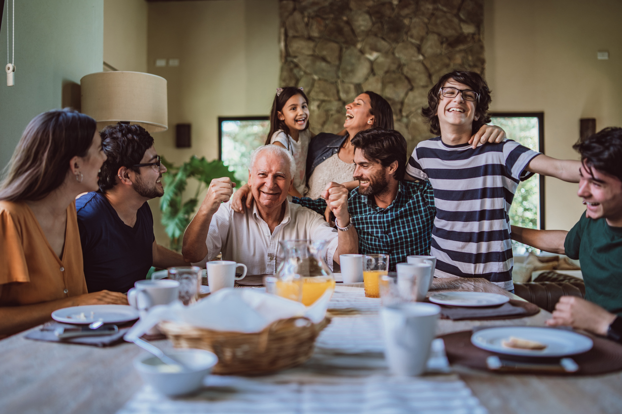 Happy smiling grandfather surrounded with his big family at breakfast.