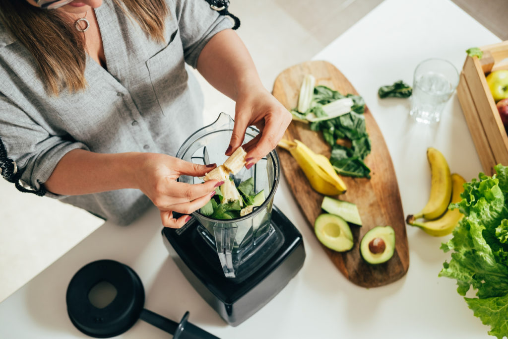 A woman making a smoothie in the kitchen with potassium-rich foods